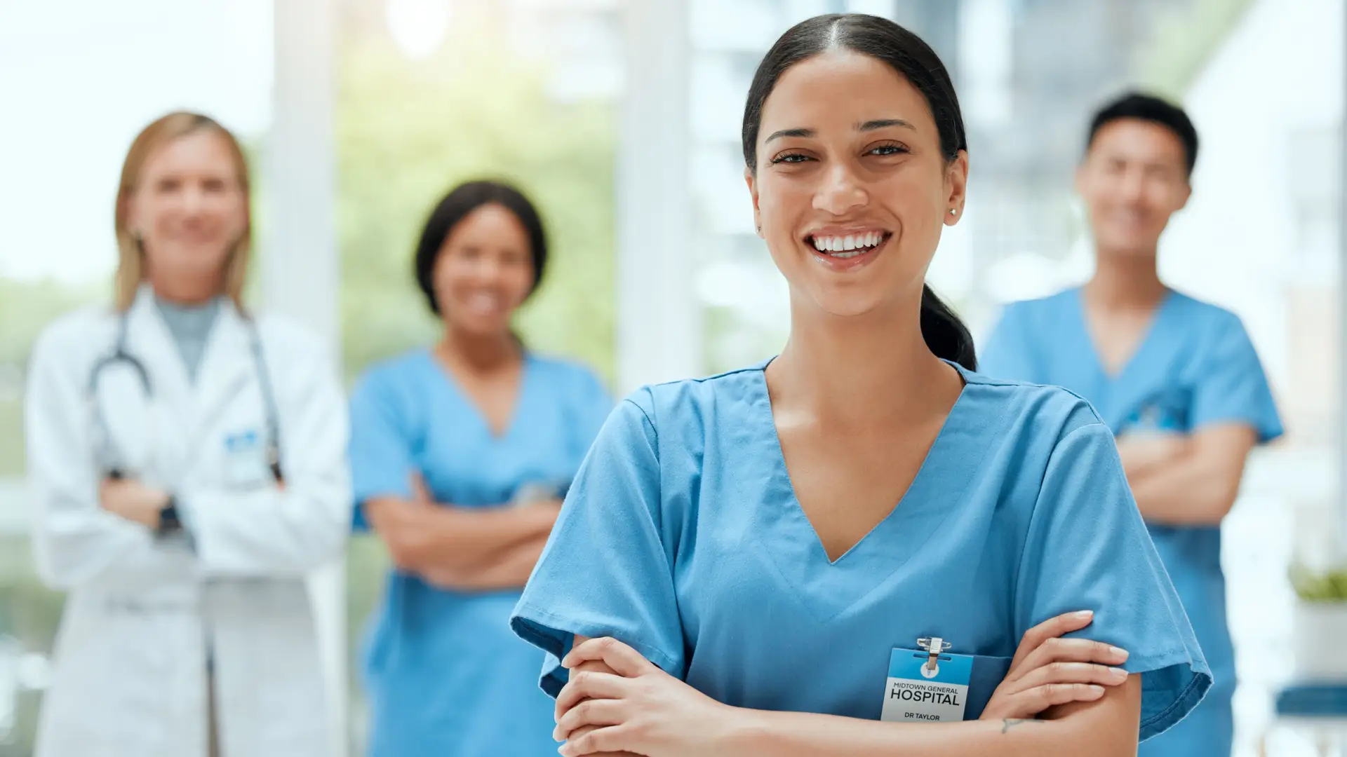 portrait, medical and a woman nurse arms crossed, standing with her team in the hospital for healthcare. leadership, medicine and teamwork with a female health professional in a clinic for treatment